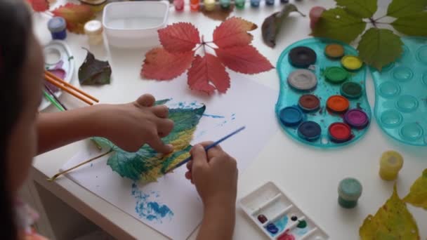 Ζωγραφική κοριτσάκι σε φθινοπωρινά κίτρινα φύλλα με γκουάς, παιδικές τέχνες, παιδική δημιουργικότητα, φθινοπωρινή τέχνη. - Πλάνα, βίντεο