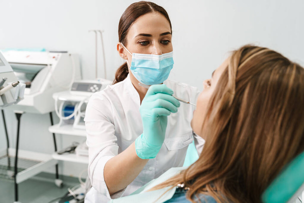 European mid dentist woman in face mask working in dental clinic - Photo, image
