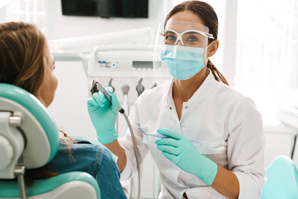European mid pleased dentist woman in face mask working in dental clinic - Foto, Bild