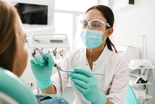 European mid dentist woman in face mask working in dental clinic - Photo, Image