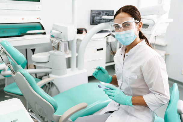 Европейская женщина-медик улыбается во время работы в стоматологической клинике - Фото, изображение