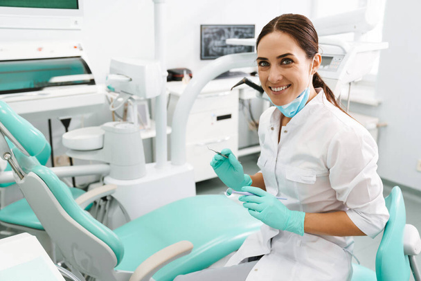 European mid dentist woman smiling while standing in dental clinic - Фото, изображение