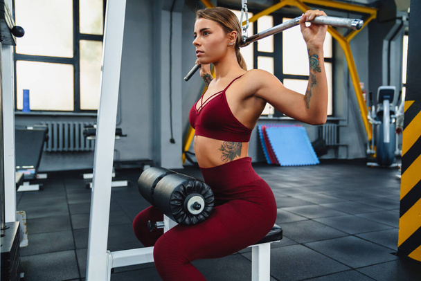 Focused athletic sportswoman doing exercise with fitness equipment while working out in gym - Фото, изображение