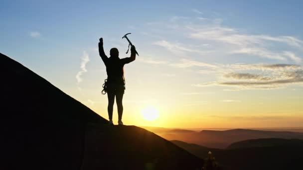 Η αργή κίνηση μιας γυναίκας ορειβάτη σηκώνει ένα τσεκούρι ενώ στέκεται σε μια πλαγιά του βουνού. - Πλάνα, βίντεο