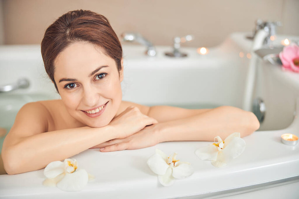 Pleasant brunette female is enjoying taking bath - Foto, immagini