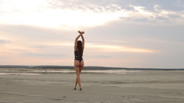 Флиртующая женщина в черном бикини гуляет по песчаному пляжу - Кадры, видео