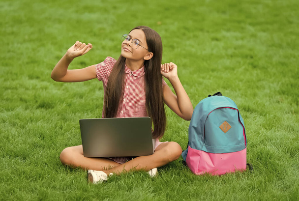 Leisure time. back to school. education online. knowledge day. kid learning private lesson. blogging. carefree girl sitting on green grass with laptop. Start up. child playing computer game - Foto, Imagen