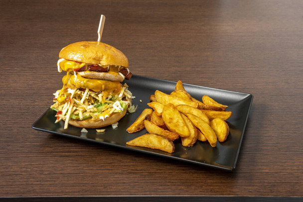 Doppel-Burger mit viel geschmolzenem Cheddar-Käse, Strohkartoffeln, Speck, Salat, Mayonnaise, Senf und Ketchup mit einer Seite Deluxe-Pommes - Foto, Bild