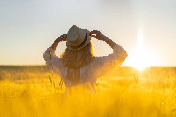 young beautiful woman with long blond hair in a white dress on a wheat field in the early morning at sunrise. Summer is the time for dreamers, flying hair, a woman running across the field in the rays of the sun. travels - Foto, immagini