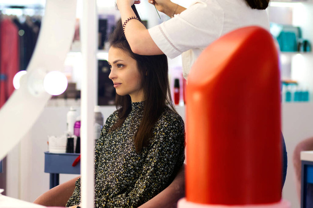 Estilista profesional crea peinado para una mujer joven en un elegante salón de belleza. Estilo contemporáneo creado por peluqueros profesionales - Foto, Imagen