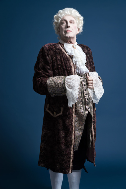 Hombre barroco retro con peluca blanca de pie y aspecto arrogante
.  - Foto, Imagen