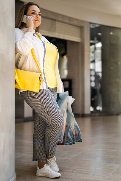 Closeup buyer woman talking smartphone smiling holding bags with purchasing at shopping mall - Fotoğraf, Görsel