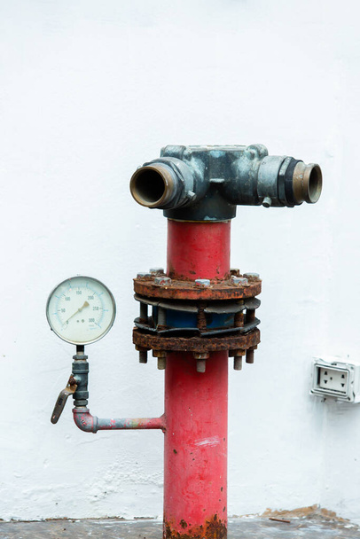 Starý červený požární hydrant v ulici s tlakoměrem namontován na bílém pozadí. - Fotografie, Obrázek