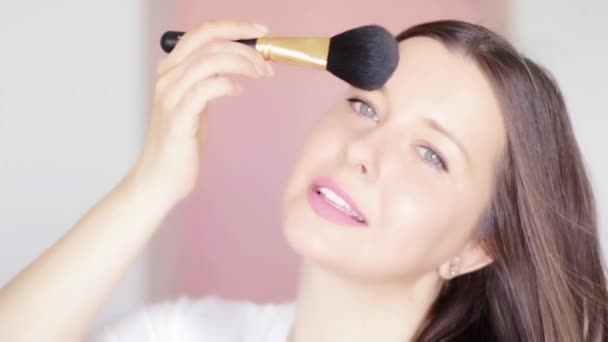 Woman with cosmetic brush applying makeup and smiling, beauty face portrait of caucasian female model on pink background, natural make-up idea, cosmetics and skincare product commercial - Footage, Video