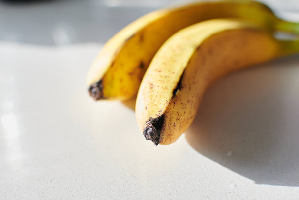 punta de plátano amarillo en cama de cocina blanca madura con manchas negras - Foto, imagen