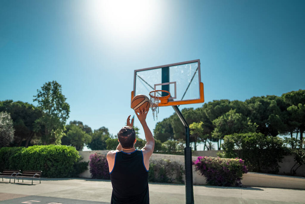 Männlicher Sportler beim Basketballwerfen auf Spielfeld - Foto, Bild