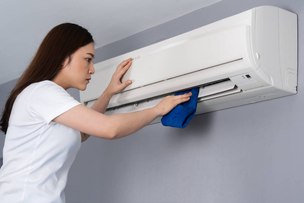 young woman cleaning the air conditioner with cloth at home - Foto, immagini