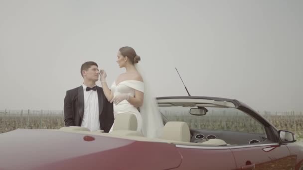 Beautiful newlyweds in car. Action.Stylish and charismatic newlyweds in car. Passionate photo shoot of newlyweds in convertible. Domineering bride and husband in love at photo shoot with convertible - Footage, Video