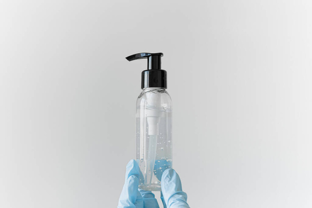 Antiseptic gel in hands in gloves on a white background - Photo, Image