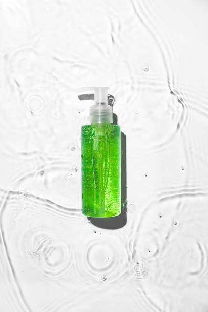 Bottle of cosmetic product in water on white background - Valokuva, kuva