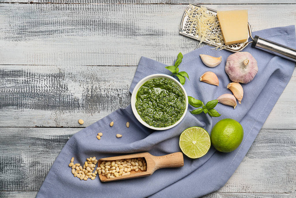 Bowl with fresh pesto sauce and ingredients on wooden table - Photo, Image