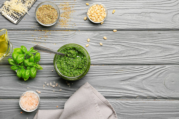 Jar with fresh pesto sauce and ingredients on wooden table - Foto, afbeelding