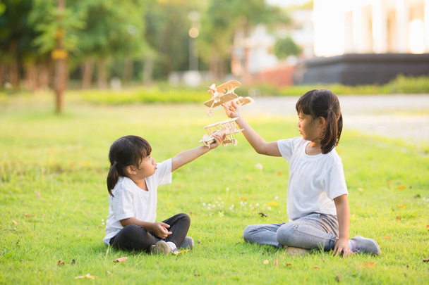 Two little kids playing with cardboard toy airplane in the park at the day time. Concept of happy game. Child having fun outdoors. - Photo, Image
