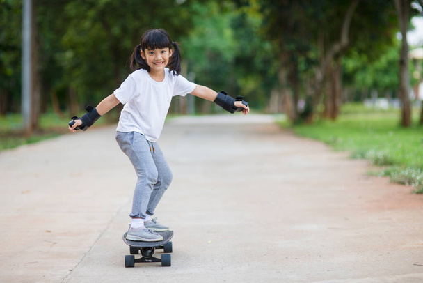 Carina bambina che gioca a skateboard o a surf skate nel skate park - Foto, immagini