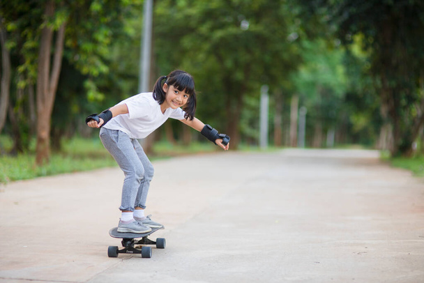 Cute little girl gra na deskorolce lub surfować na łyżwach w skate parku - Zdjęcie, obraz