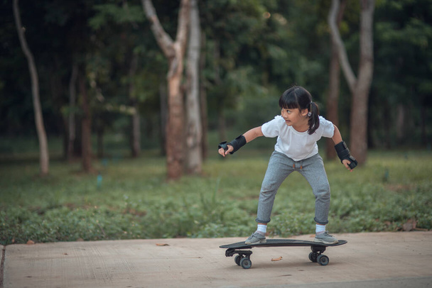 Petite fille mignonne jouant au skateboard ou au surf skate dans le skate park - Photo, image