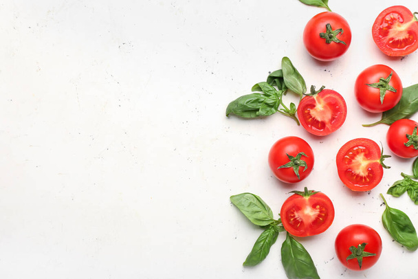 Frische reife Tomaten und Basilikumblätter auf hellem Hintergrund - Foto, Bild