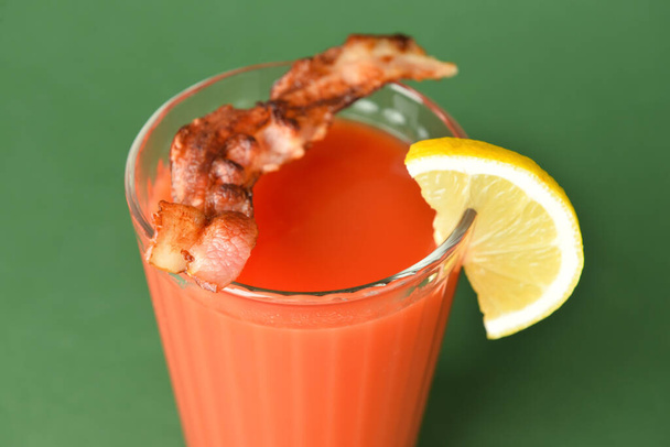Glass of bloody mary cocktail garnished with bacon and lemon on color background, closeup - Valokuva, kuva