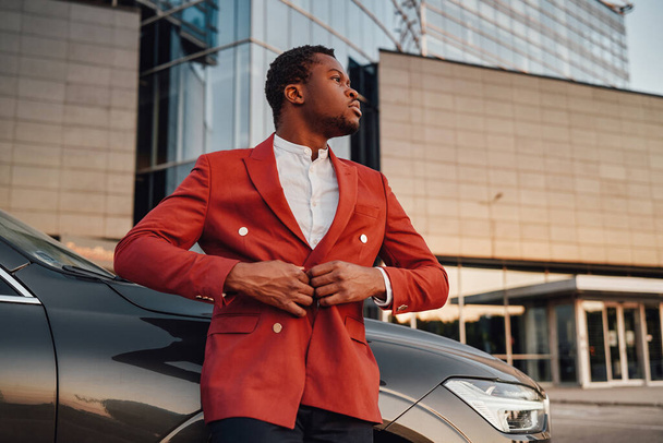 Cool Afrikaans zakenman poseren tegen gebouw met zijn auto - Foto, afbeelding