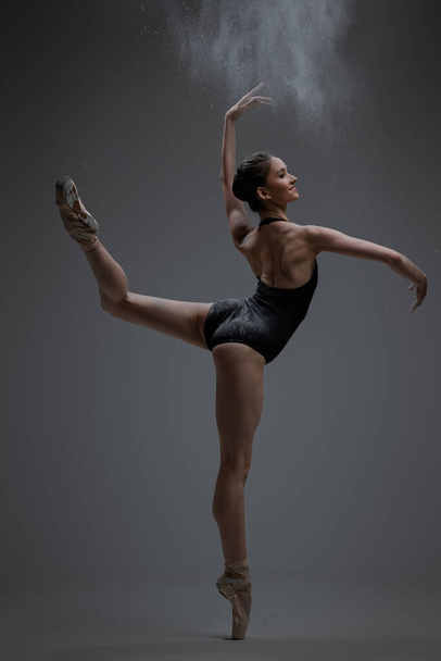 Gracieuze ballerina spuiten stof en dansen in de studio - Foto, afbeelding