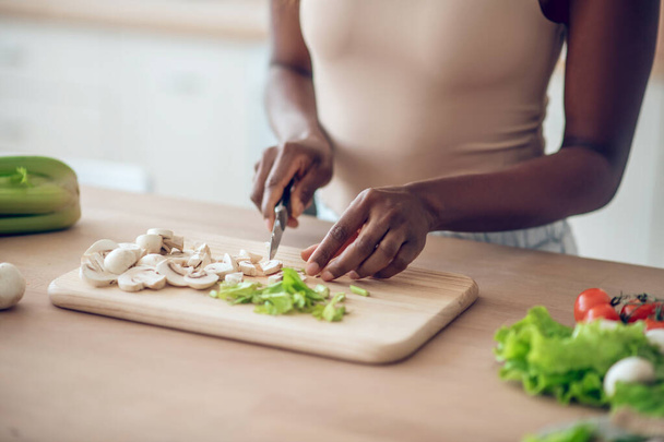 Hands of african american woman chopping vegetables with knife - Photo, image