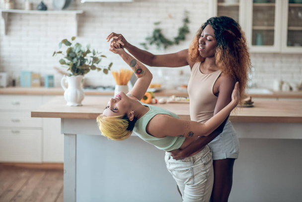 Dark-skinned woman supporting caucasian girlfriend in dance - Valokuva, kuva