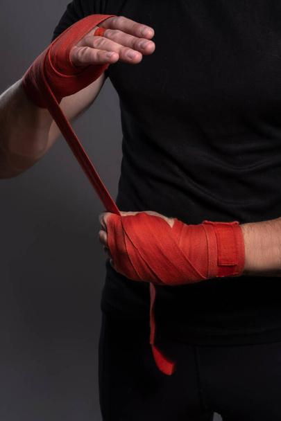Manos masculinas envueltas con cinta de boxeo roja antes de la pelea - Foto, Imagen