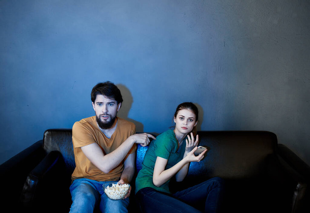 νεαρό ζευγάρι κάθεται στον καναπέ το βράδυ βλέποντας τηλεόραση ποπ κορν υπόλοιπο - Φωτογραφία, εικόνα