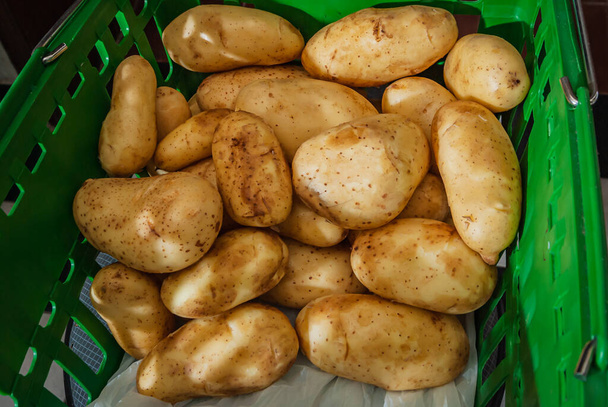Pile de pommes de terre biologiques crues fraîches sur le panier du marché vert. Ferme fraîche. vue de dessus de près. Un tas de racines de pomme de terre. Légumes pour purée de pommes de terre, frites, frites. - Photo, image