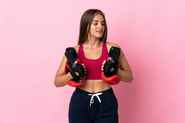 若いウルグアイの女性は、ボクシングの手袋でピンクの背景に隔離 - 写真・画像