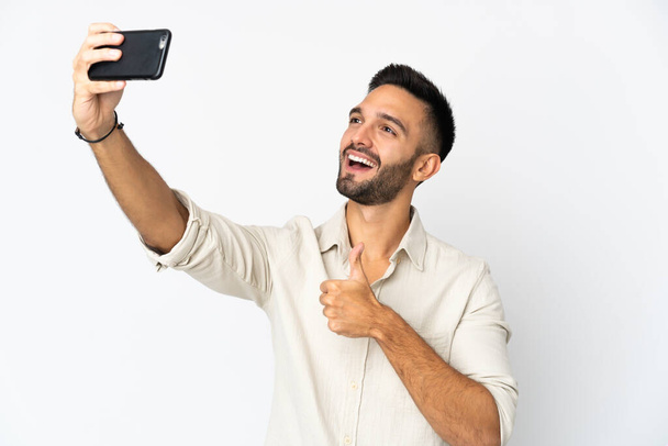 Nuori valkoihoinen mies eristyksissä valkoisella taustalla tehden selfien matkapuhelimella - Valokuva, kuva
