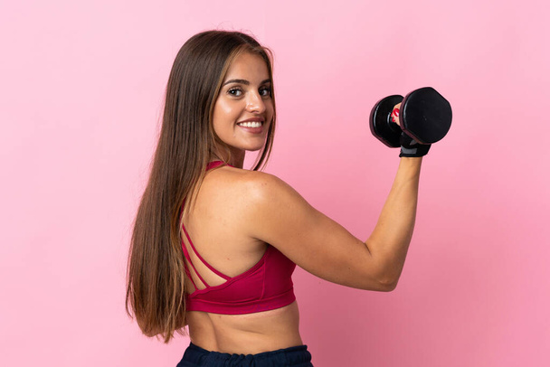 Young Uruguayan woman isolated on pink background making weightlifting - Фото, изображение