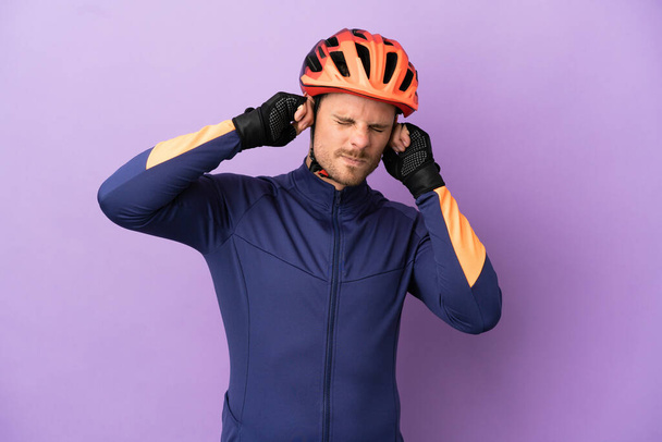 若いブラジル人サイクリスト男は紫の背景に不満とカバー耳に隔離 - 写真・画像