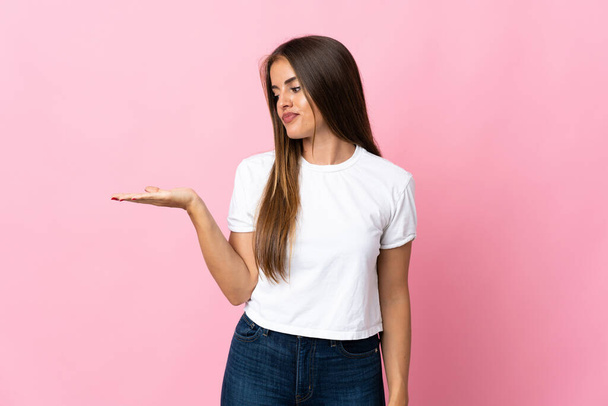 Young Uruguayan woman isolated on pink background holding copyspace with doubts - Photo, Image