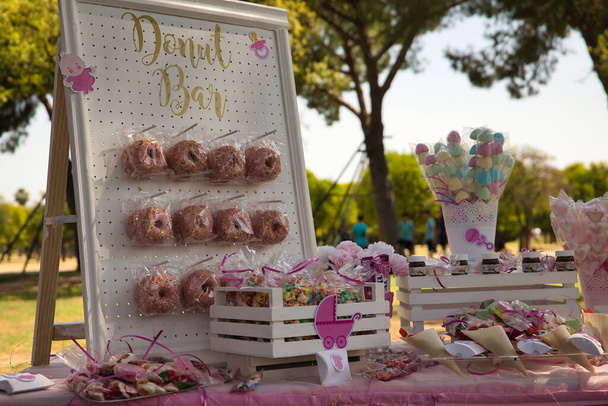 Asztal cukorkával és rózsaszín fánkkal egy babaköszöntő ünnepségen. - Fotó, kép