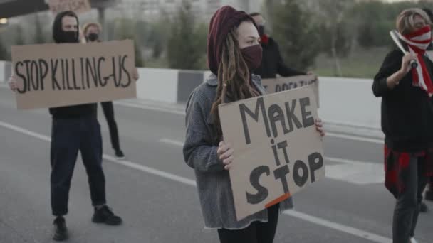 Кишеньковий повільний знімок чоловічих і жіночих протестувальниць у масках, що тримають знаки і блокують шосе
 - Кадри, відео