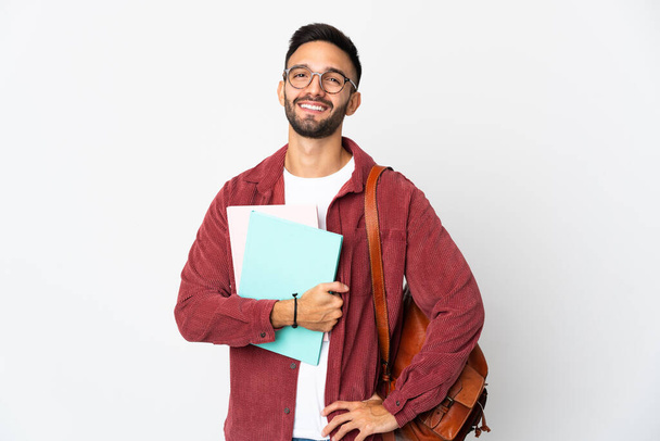 Jeune étudiant homme isolé sur fond blanc posant avec les bras à la hanche et souriant - Photo, image
