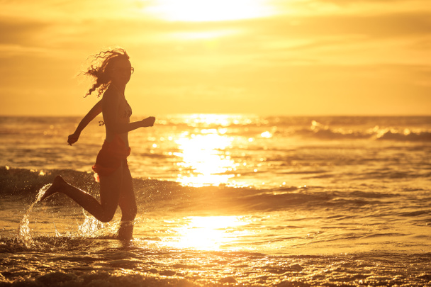 Nainen juoksee rannalla aamunkoitteessa
 - Valokuva, kuva