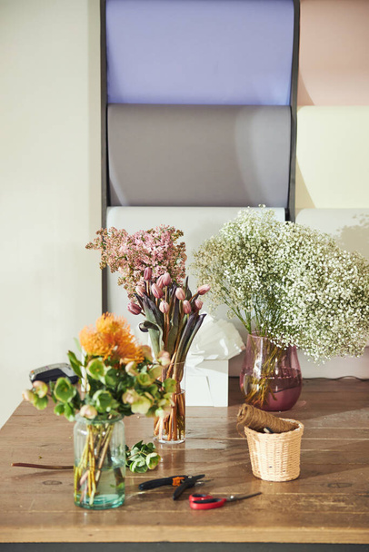 Три красивые сгустка в прозрачных стеклянных вазах на солнечном деревянном столе - Фото, изображение