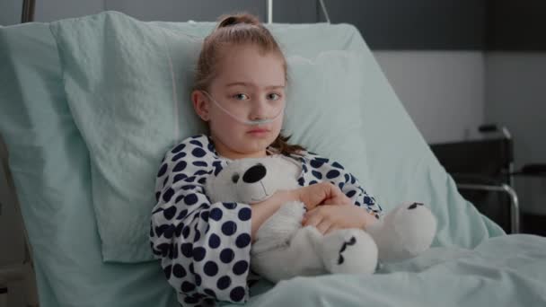 Portrait of little girl patient wearing oxygen nasal tube resting in bed recovery - Footage, Video